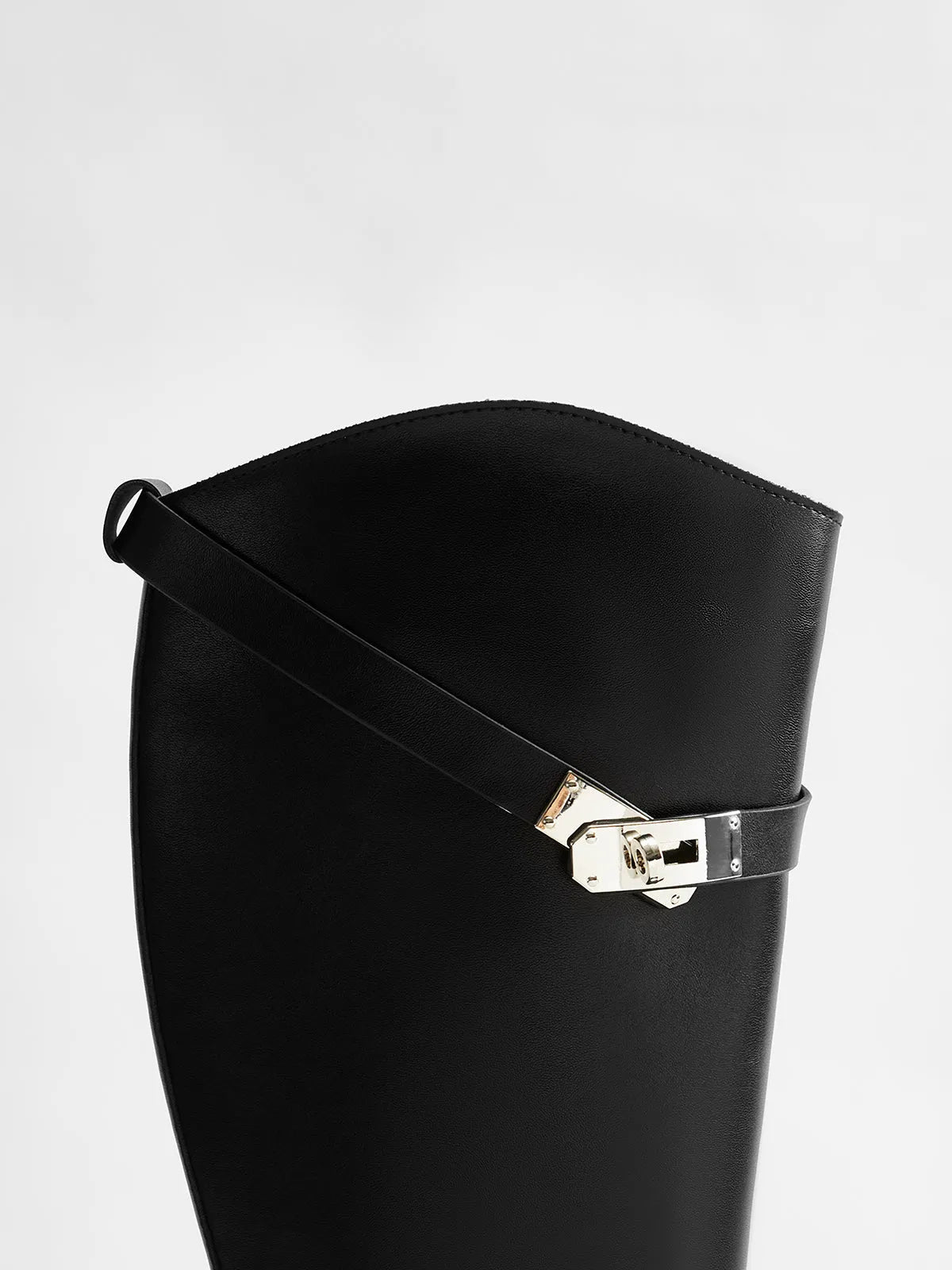 Close-up of the silver-tone buckle and diagonal strap on a black knee-high boot.